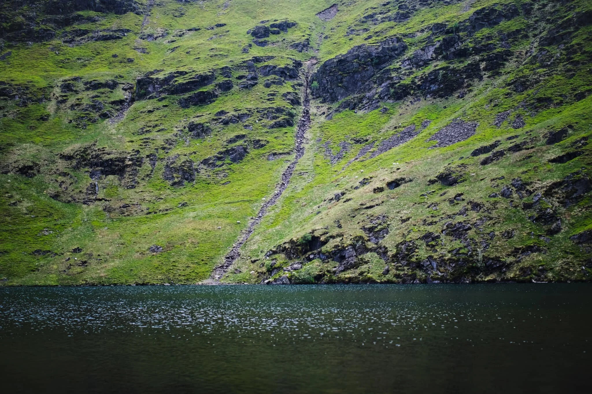 An unnamed gill cuts through the crags of Bowscale Fell and drops into the deep and dark water of Bowscale Tarn.