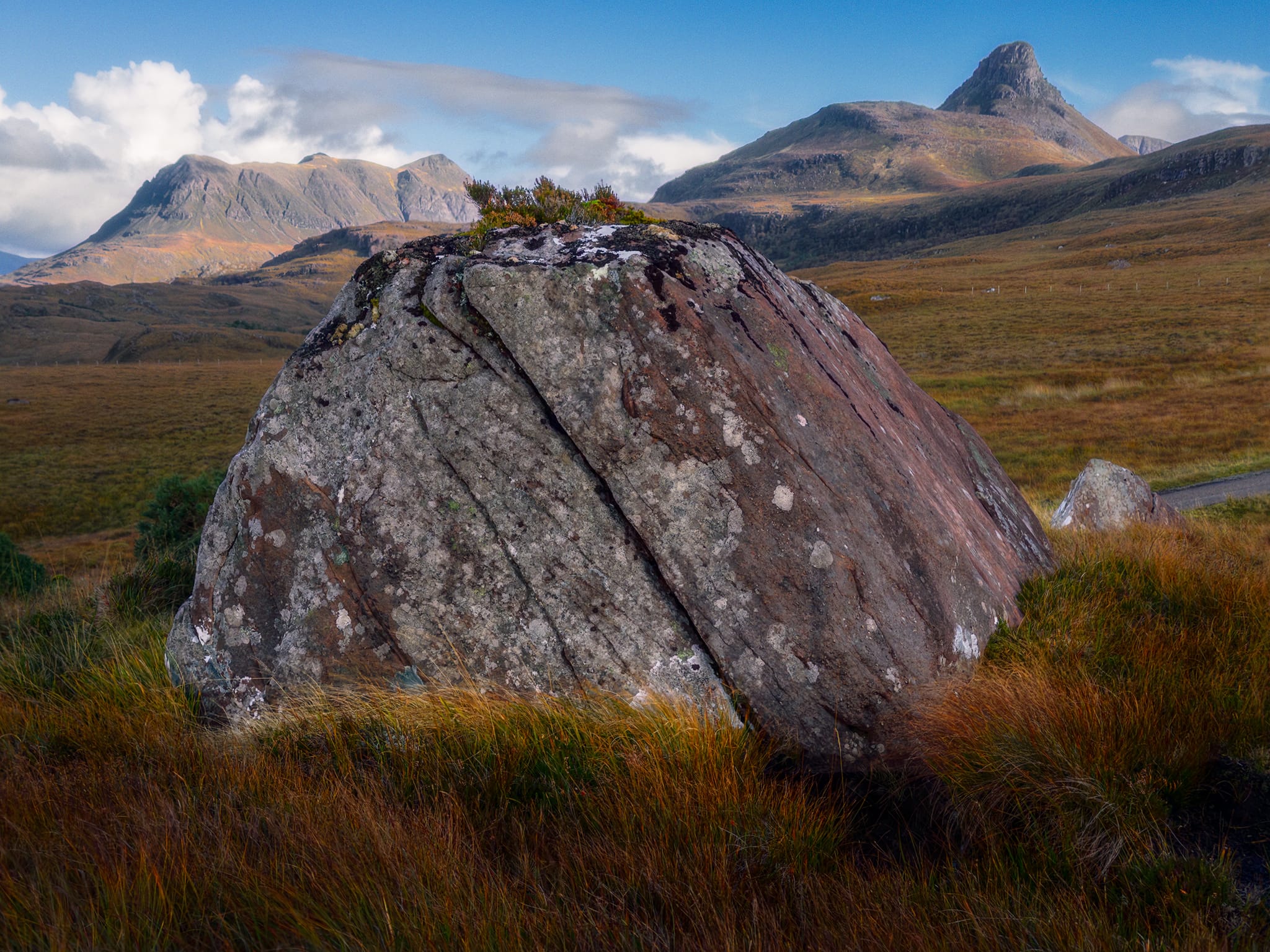 Below my solitary perched boulder, a large one embedded in the grass provided another composition for me. I used its hulking mass and shape as a leading line and separator between the distance mountains of Stac Pollaidh and Cùl Mòr.