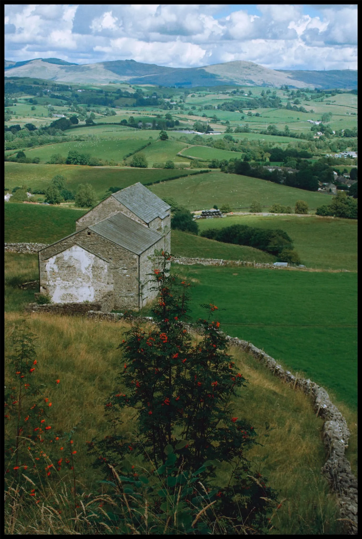  At these disused barns the path rounds Helsfell Nab and climbs sharply up. You&rsquo;re then above the A591, where you cross the bridge over the road to continue on towards Cunswick Scar. 