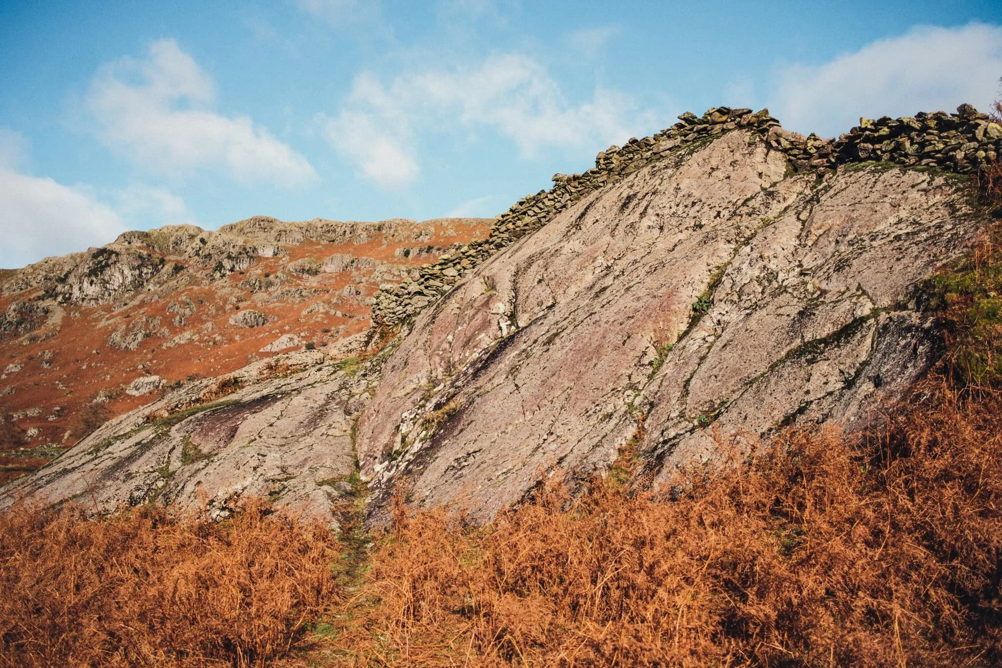  Post-lunch, we followed the craggy trail east back towards Grasmere. This giant boulder above us gained our interest, largely for the addition of a drystone wall perched on top of it! 