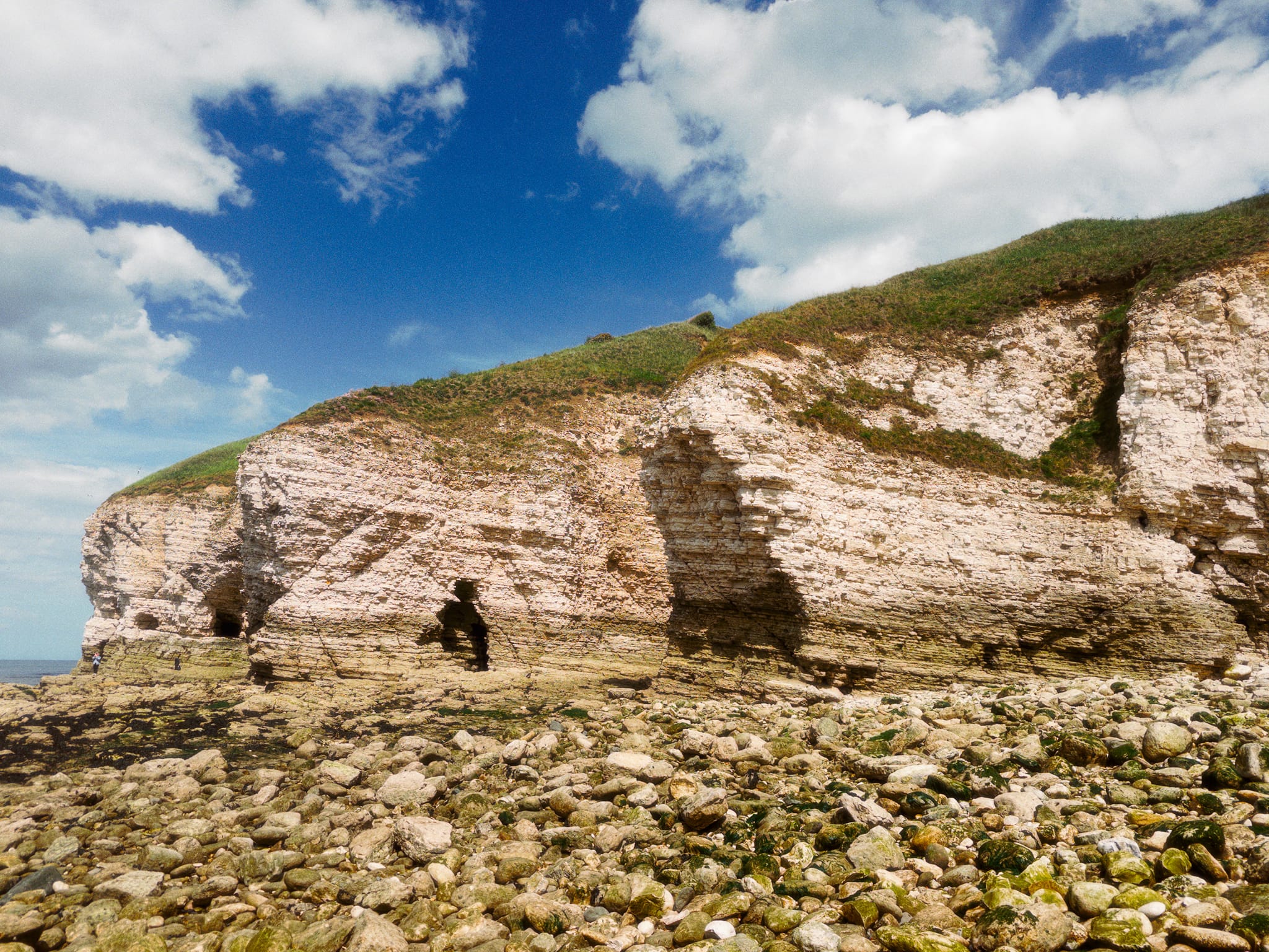 The eastern cliffs of North Landing, featuring the eroded strata and numerous little caves pockmarked across the cliffs.