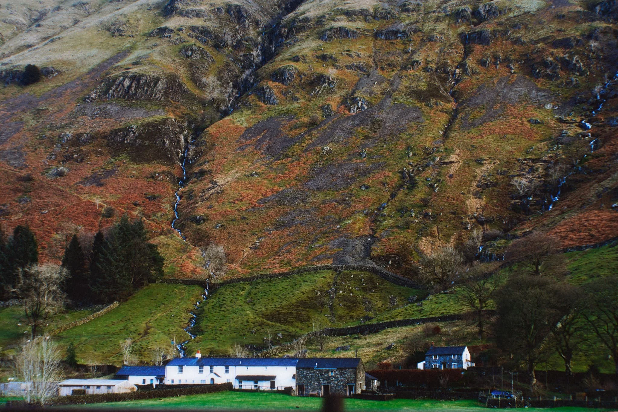  Further south on the A591, near Thirlmere, Fisherplace Gill cuts a deep fissure within the crags of the Helvellyn massif. The farmhouses below look miniscule in comparison. 