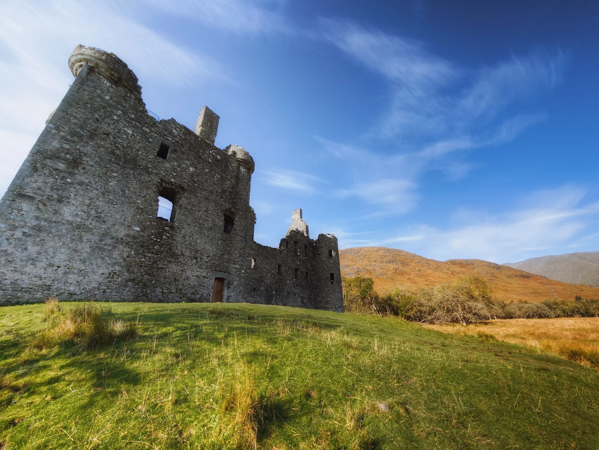 An ultra-wide perspective of the front of Kilchurn Castle, with the slopes of  Ben Cruachan  in the distance and some beautiful wispy clouds above. 