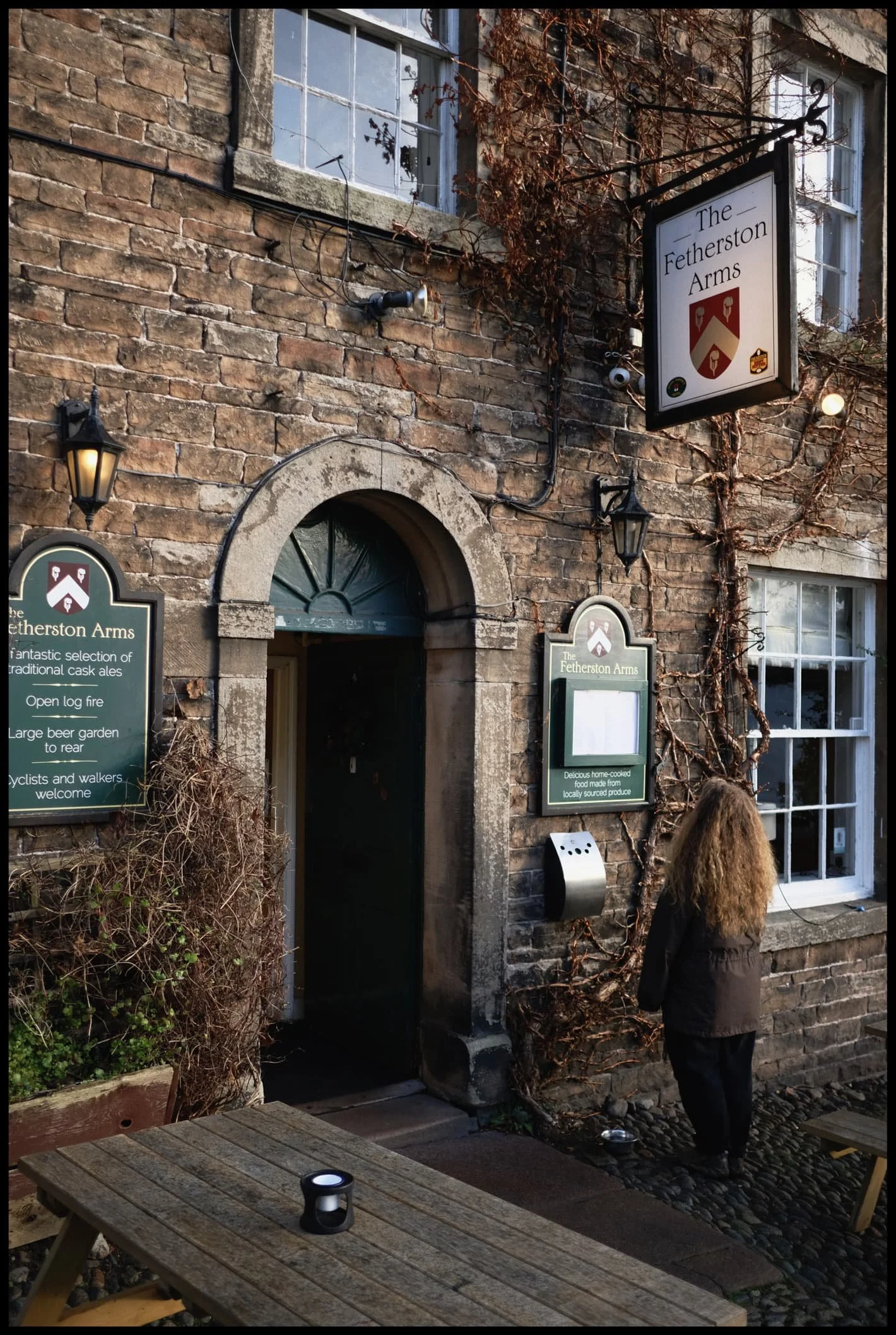  On t&rsquo;other side of t&rsquo;road, Lisabet inspects the menu for the Featherston Arms. 