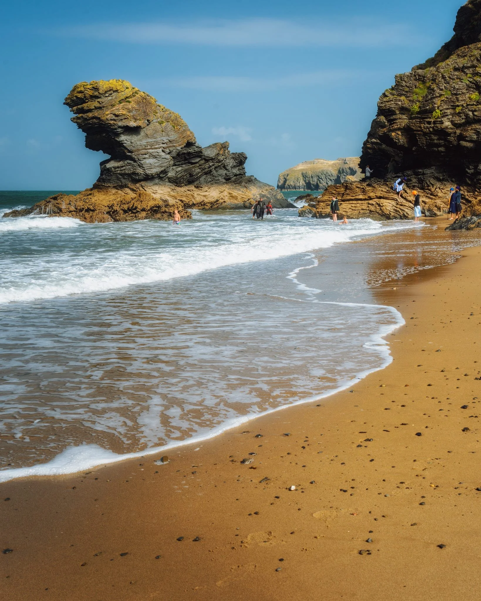  A simpler image of  Carreg Bica , with people playing around its base for scale. I waited for the rising tidal waves and shot multiple frames to get the waves in just the right shape and angle. 