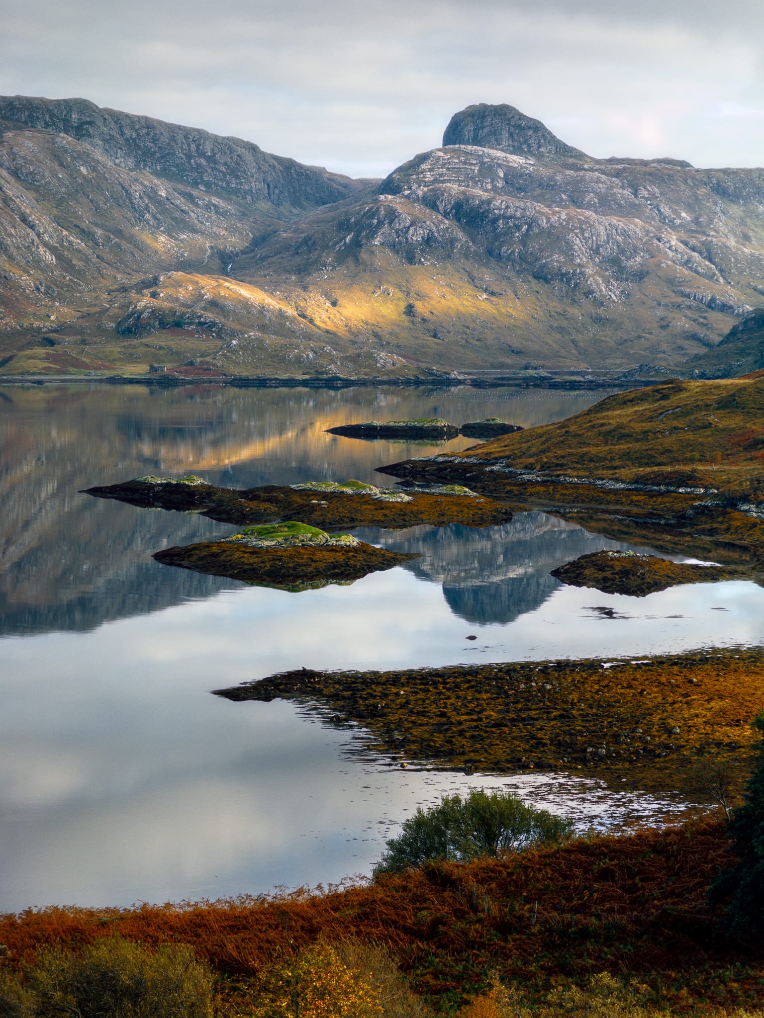 Further north along the A894, the sight east across Loch Gleann Dubh stopped us dead. Absolutely perfect reflections. How could we not? The distinctive knuckly peak reflected in the loch is the Stack of Glencoul, its flanks catching a lovely sliver of golden light.