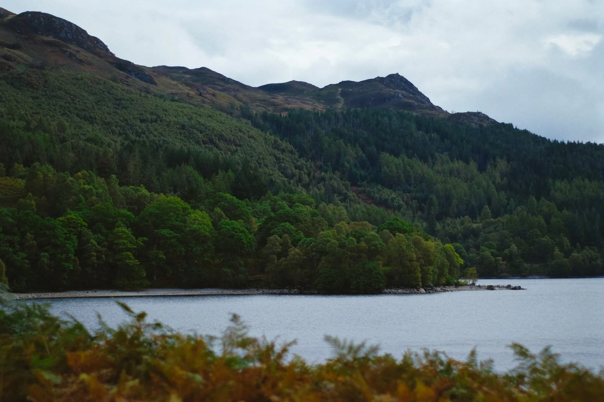  We eventually reached a spit of land—variously known as either Brenachoile Point or  Ruinn Dubh Aird —that protrudes out into the loch, affording us fantastic views all the way up and down Loch Katrine. Looking east, the unmistakeable profile of Ben A&rsquo;an comes into view and I shot this photo; a mental bookmark to return to this area again and summit that hill. 