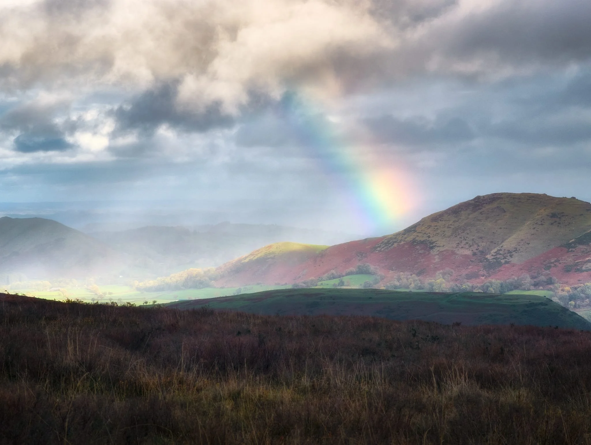  Soon afterwards we &ldquo;enjoyed&rdquo; a series of squalls drenching us. However, that did mean we got this superb light show of a rainbow hitting Caer Caradoc and a focused spotlight illuminating the northern Stretton Gap. 