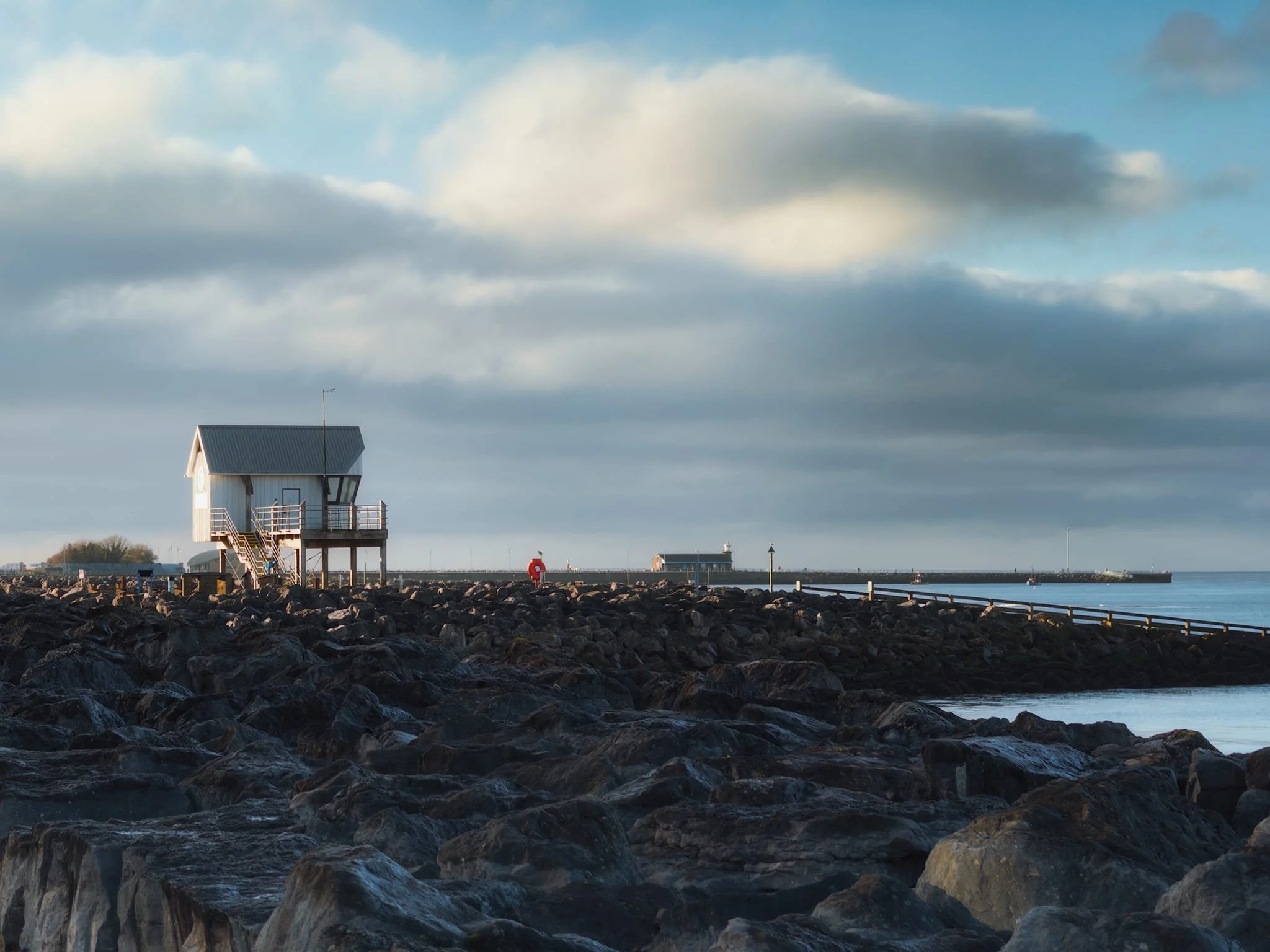  The boat office of Morecambe Sailing Club catching the brilliant winter light above Morecambe&rsquo;s extensive boulder breakwaters. Rushing clouds above moved in. 