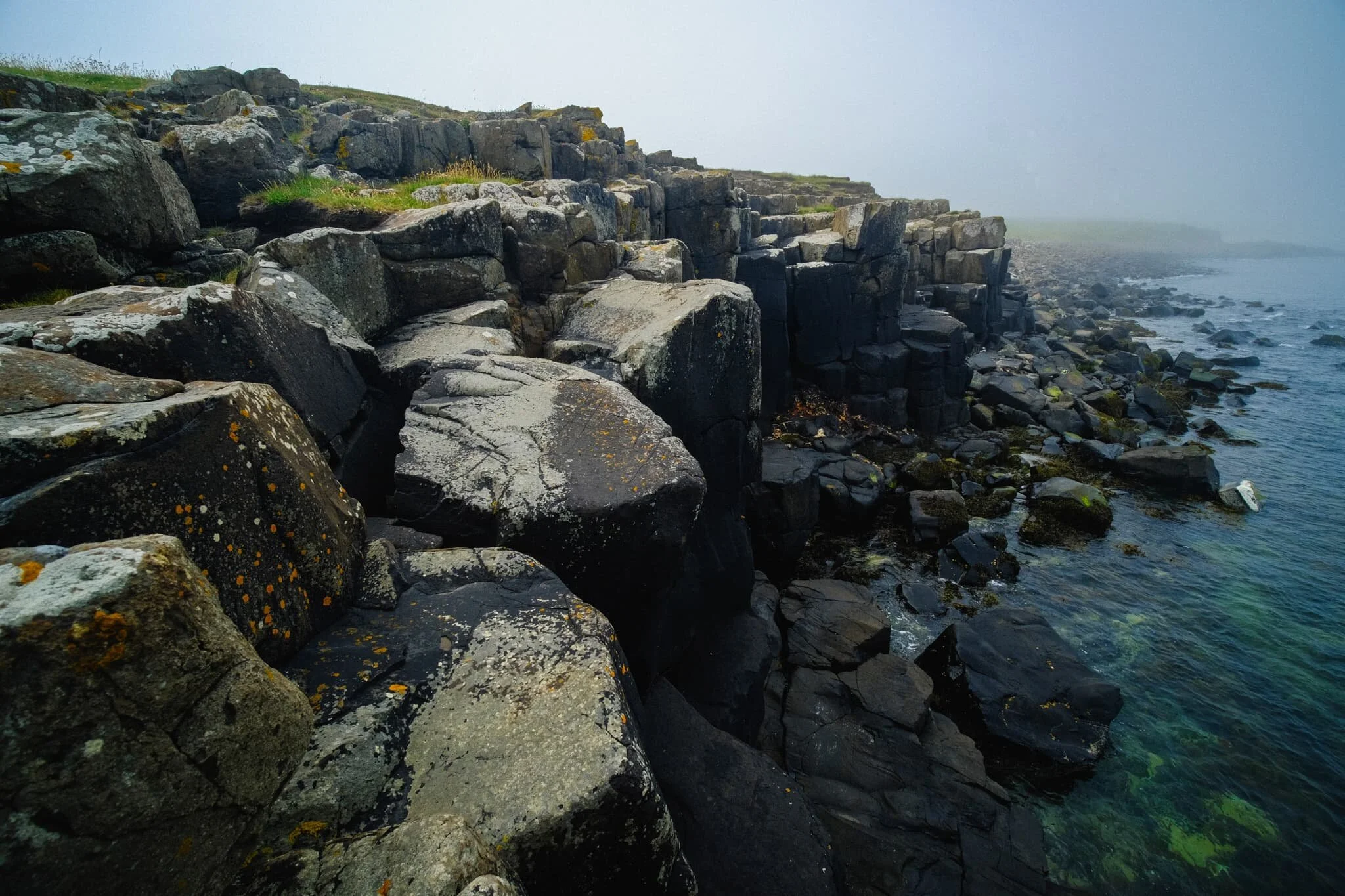  Columns of dark volcanic basalt stand as a fortress against the unrelenting sea. 
