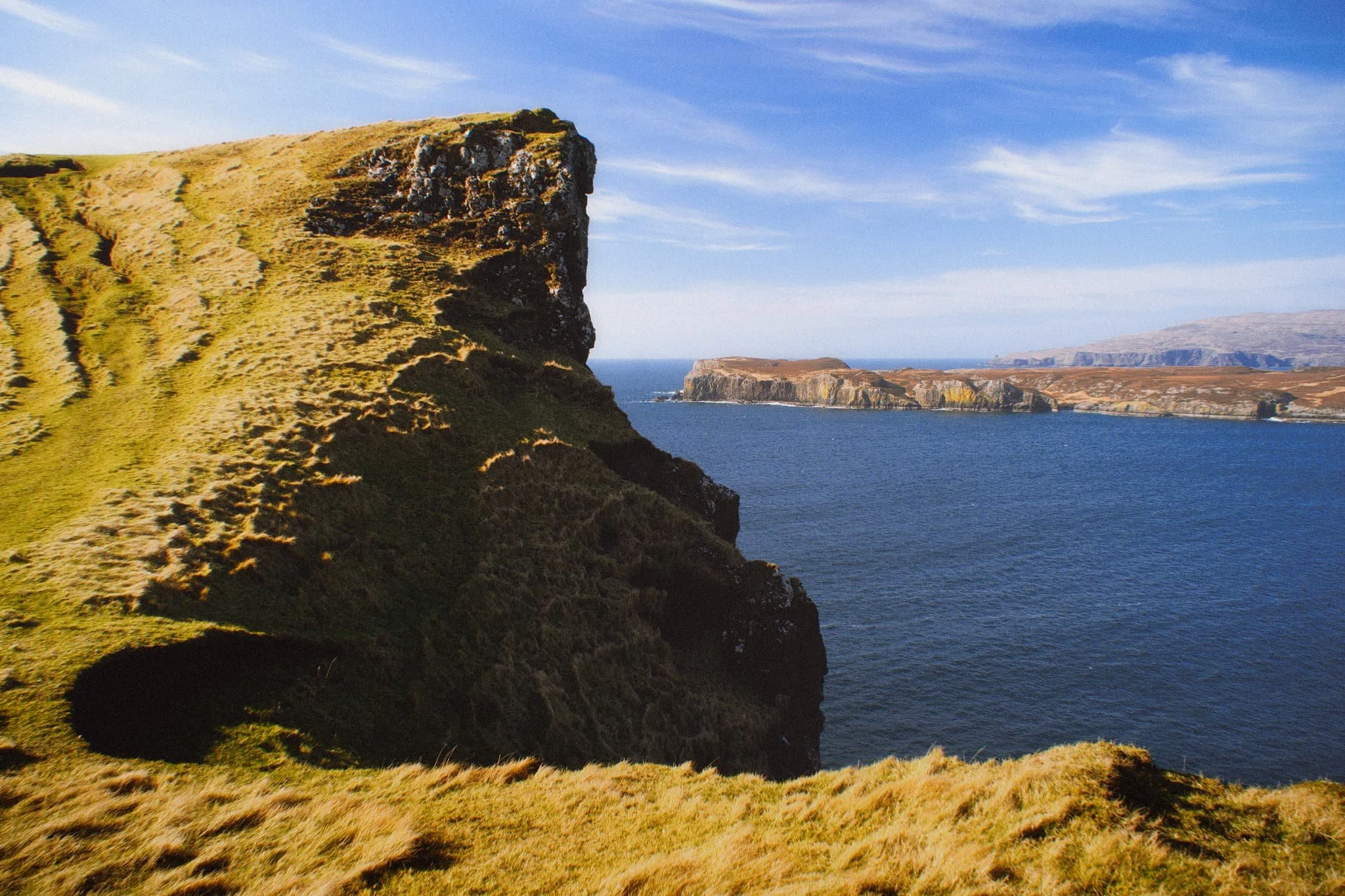 Looking back at the tallest cliff, it’s contrasty shape and shadow is used to frame the distant island of Wiay and Duirinish cliffs.