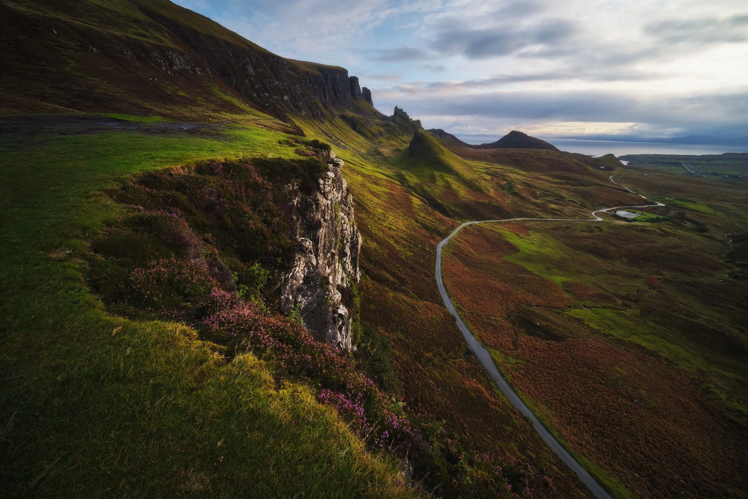  Now following the northeastern ridge of the Quiraing, we found a lovely load of heather still largely in bloom. I composed this ultra-wide view of the Quiraing as I liked the way the curving cliff mirrored the curve of the road below. 