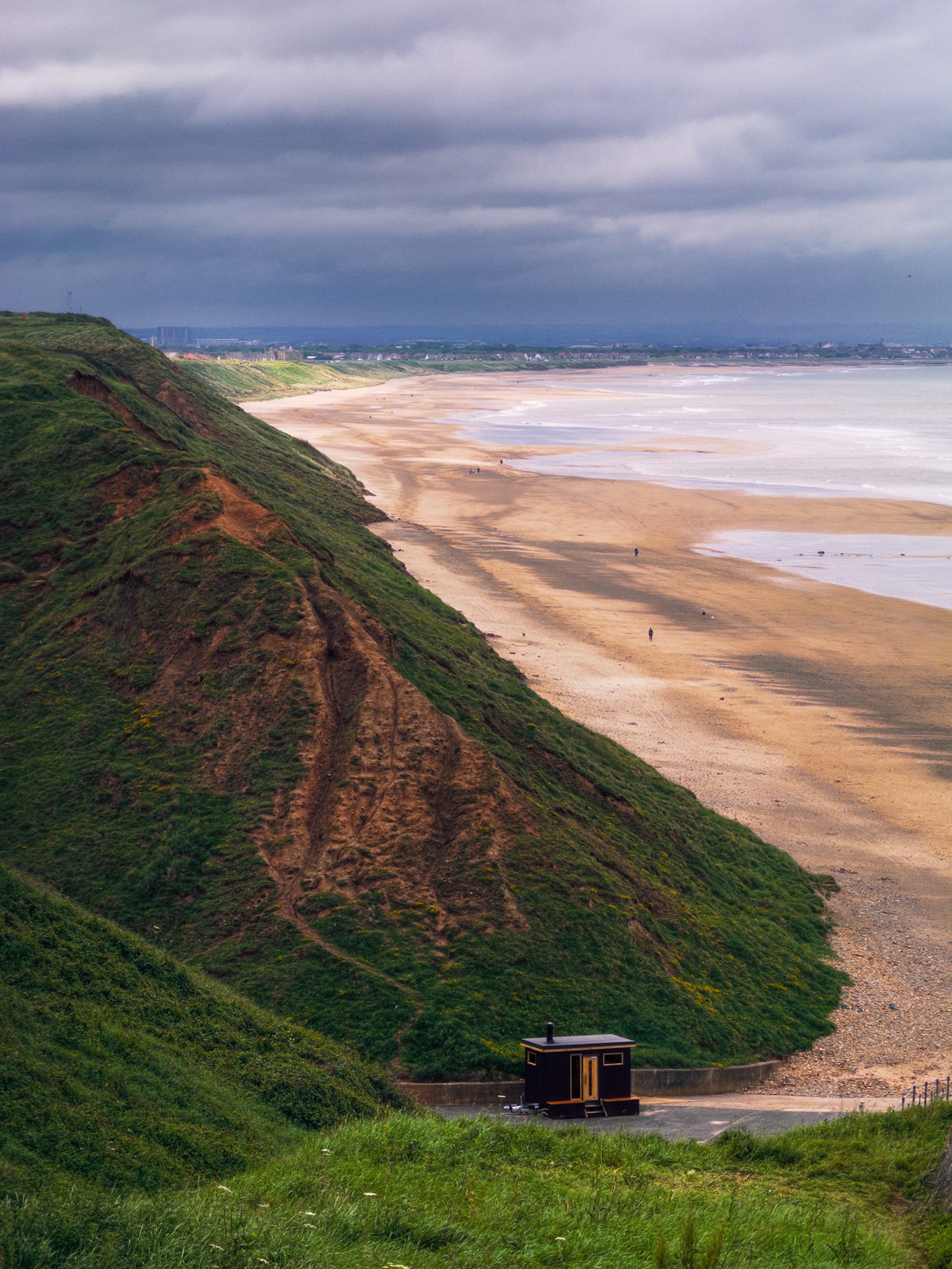 Looking north along the cliffs and dunes towards the beaches of Saltburn and Marske as a dark storm rolls in from the industrial town of Redcar.