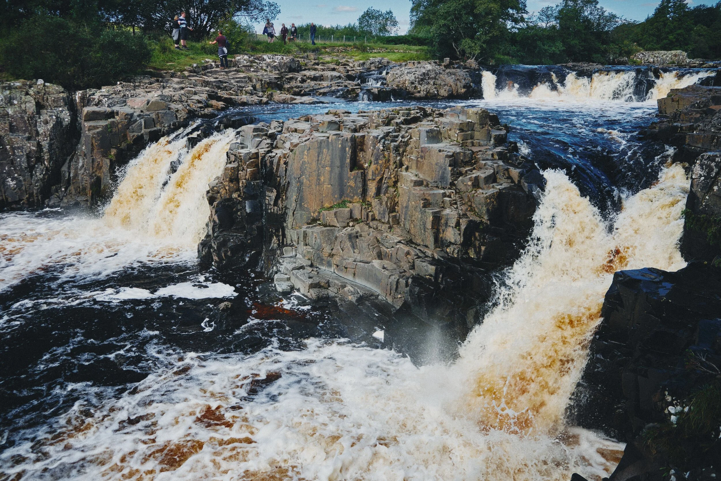You can more clearly see the rigid column structures that the Whin Sill rock is known for. Fellow hikers in the background provide a good sense of scale.