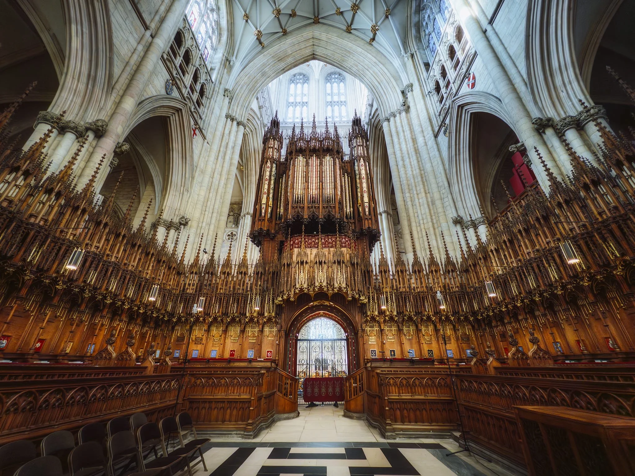 York Minster’s magnificent organ in the Quire. The organ dates to 1632 when Charles I funded its construction, moving from the choir’s north side to the screen in 1690. Described in 1730 as an elaborate instrument painted with the 150th Psalm, it was expanded by John Camidge into Britain’s largest before the 1829 fire destroyed it. Elliot and Hill built an 8,000-pipe replacement in 1832—then the world’s biggest—which was rebuilt in 1859 and 1903. It was modernided in 1918 and 1931, then more neo-classical elements added in 1960. Damaged in the 1984 fire, it was restored in 1991–1993 and completely refurbished in 2018–2021.